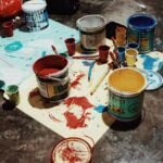 Colores Artistic mess of various colored paint cans and brushes on a studio floor.